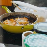 Delicious food being fried in a pan on an induction stove, surrounded by kitchen items.