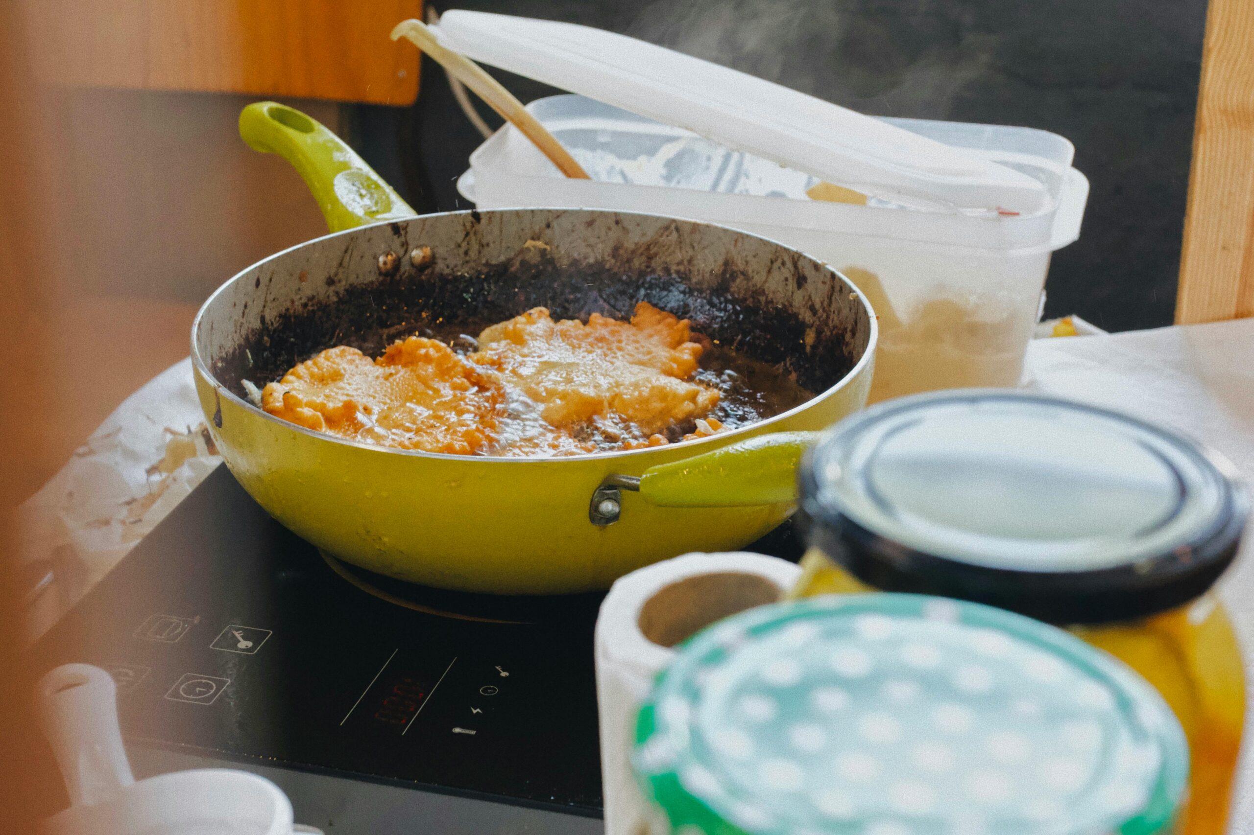 Delicious food being fried in a pan on an induction stove, surrounded by kitchen items.