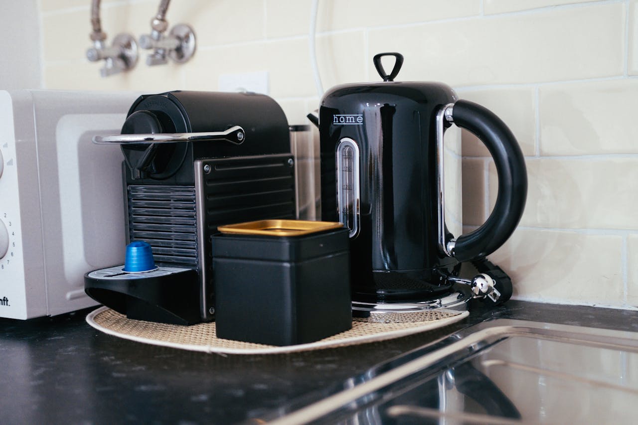 Sleek black coffee maker and kettle on a modern kitchen countertop, ideal for brewing.