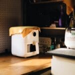 Top 12 Best Air Fryer Under $150 for Crispy Food (2026 Guide) A warmly lit kitchen corner featuring a modern appliance with a cloth cover on a wooden counter.