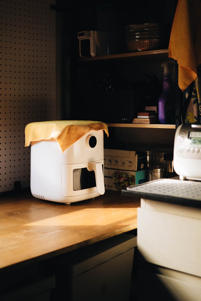 A warmly lit kitchen corner featuring a modern appliance with a cloth cover on a wooden counter.